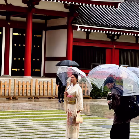 Women dress in traditional kimono robes being photographed in the rain